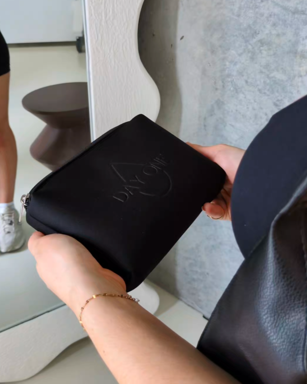 Stylish black personal care bag for periods held in her hands ready to use for any period emergency.