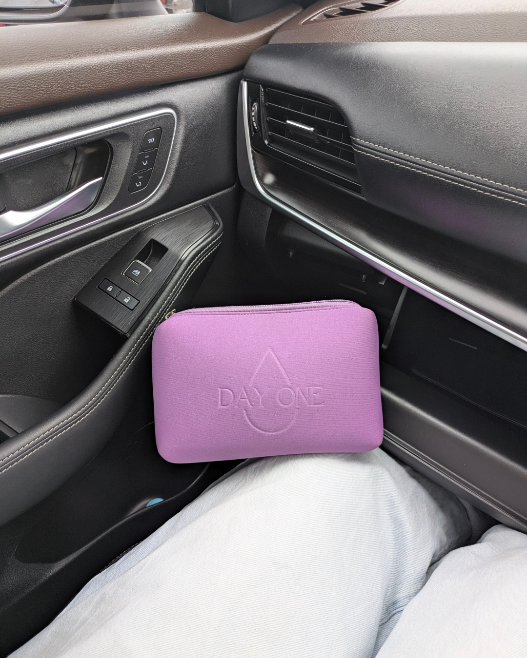 Purple Period kit for girls in car with reusable wet pouch and pill tin for on-the-go use.